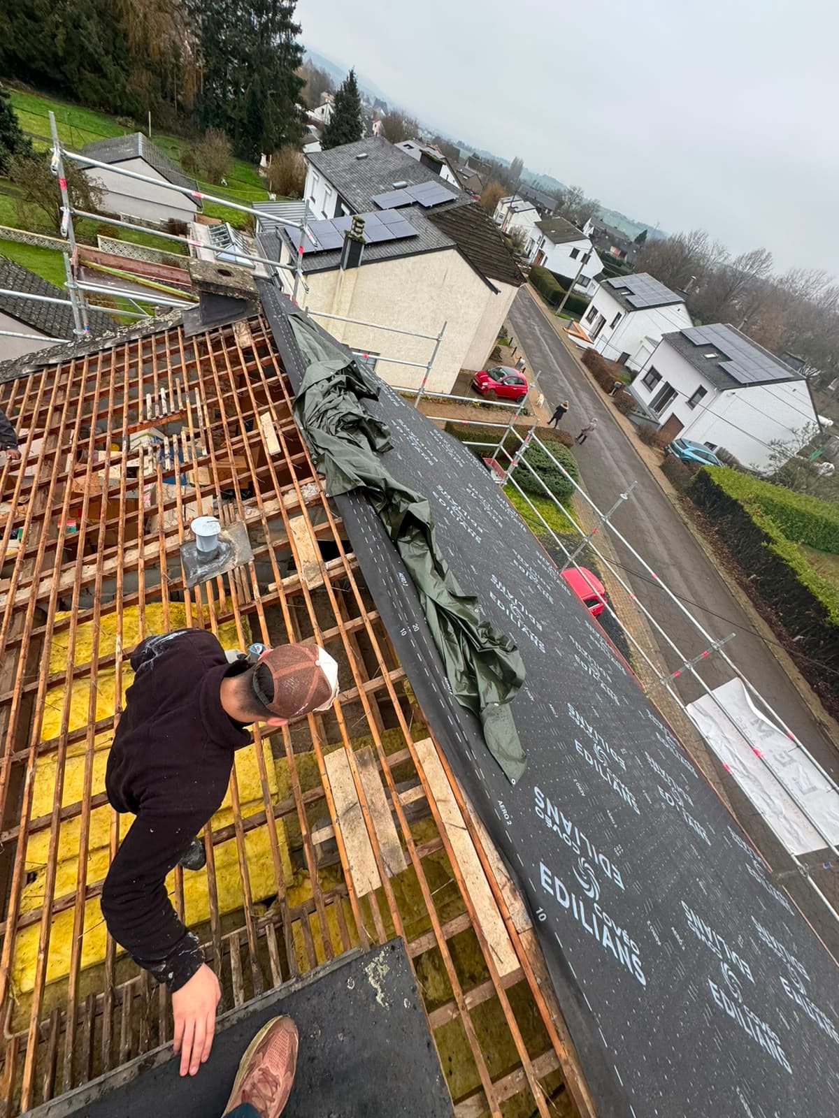 Chantier de rénovation lourde vue depuis le faîte, charpente à nu et lattage neuf, Aubange